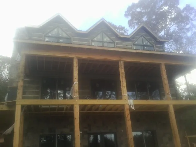 Dormers and porch framing on a large log home under construction — Roof Coating work by our crew in Mount Airy