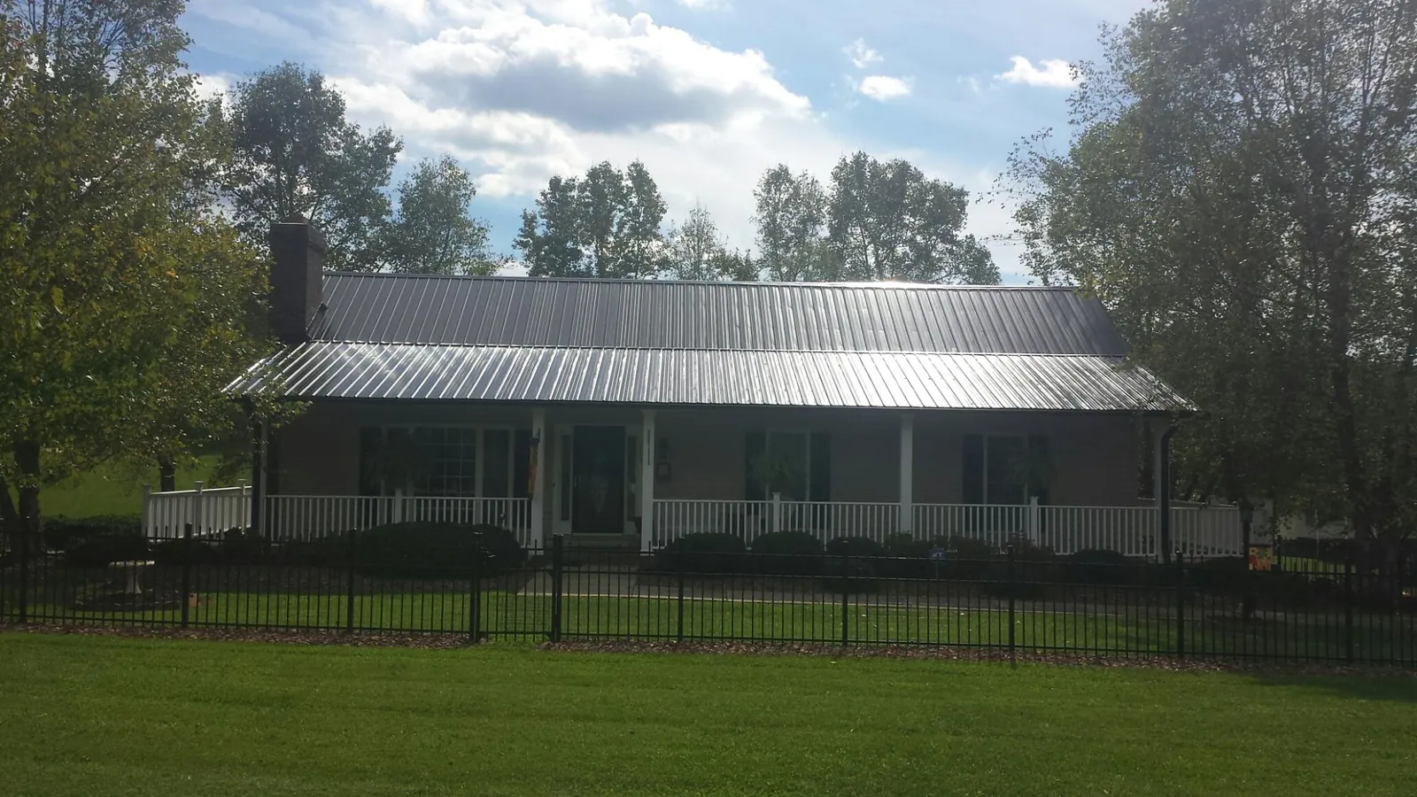 Gray metal roof on a brick ranch with a full width front porch — Gutter Guard Installation work by our crew in Mount Airy