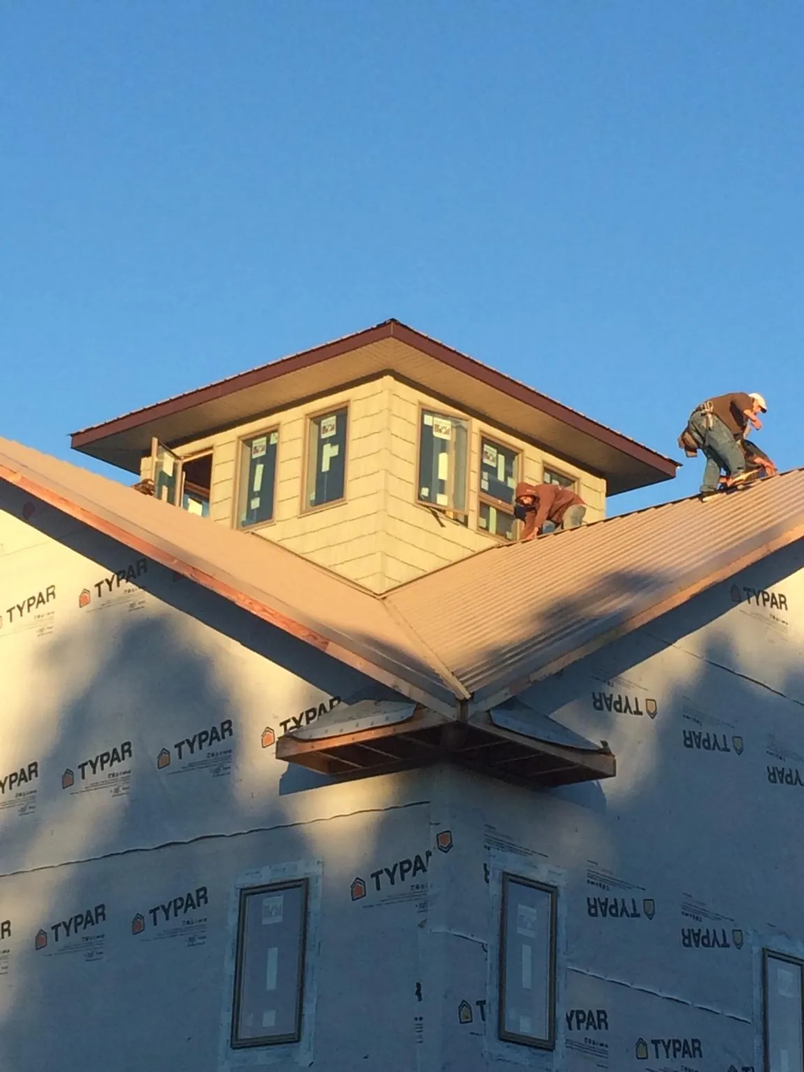 Roofers working around a rooftop cupola on a new metal roof at sunset — Roof Waterproofing in Mount Airy by Roofing Brothers